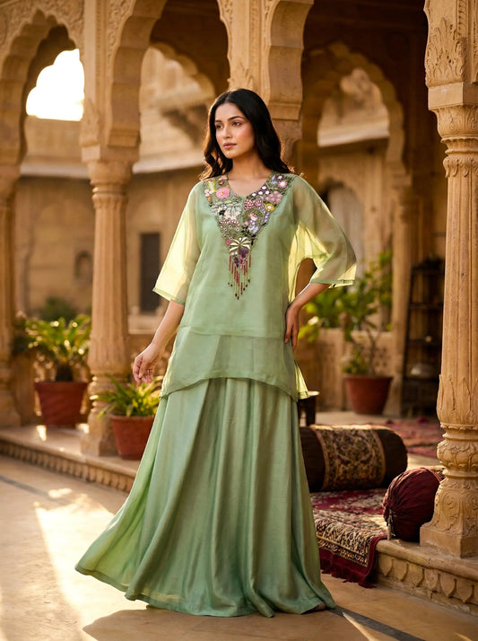 Woman in a pastel green silk ethnic ensemble with floral embroidery, standing in a palace courtyard