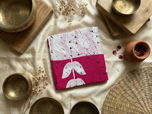 Folded soft silk saree with pink and white abstract leaf design, surrounded by brass bowls and dried flowers
