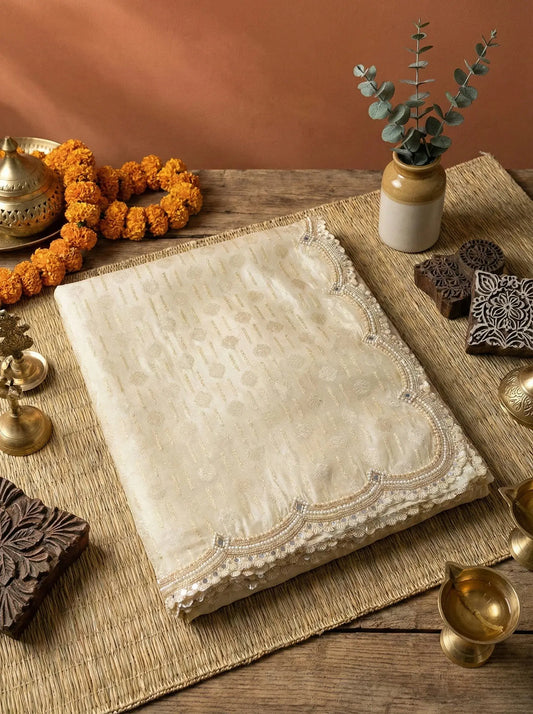 Folded cream soft silk saree with gold detailing and scalloped embroidered border on rustic table setting