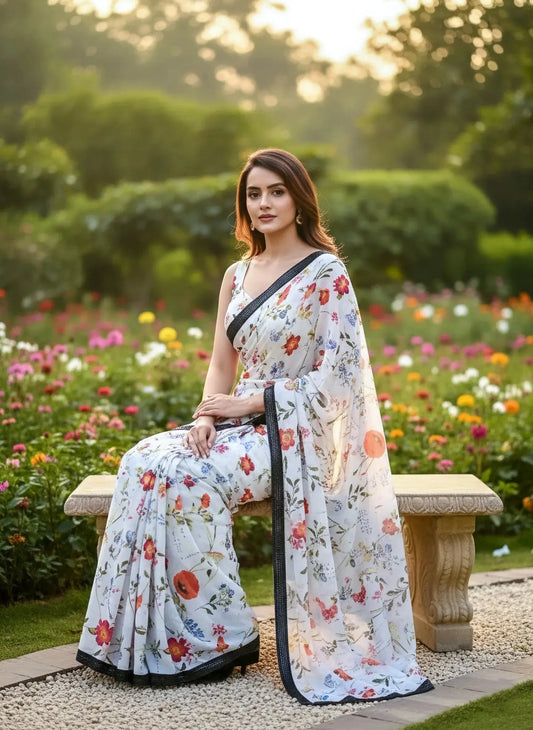 Woman in a white floral print silk saree sitting on a bench in a garden with flowers