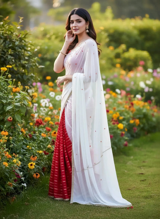 Woman wearing a red and white soft silk saree with gold jewelry, standing in a flower garden