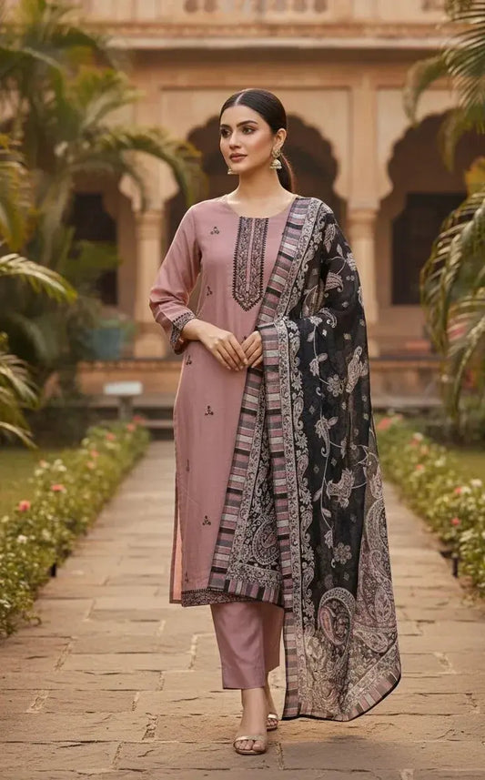 Woman in mauve embroidered kurta set with black printed dupatta, standing in garden courtyard