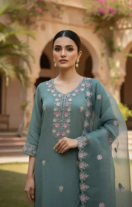 Woman in pastel blue embroidered silk saree with pink floral patterns, outdoor setting