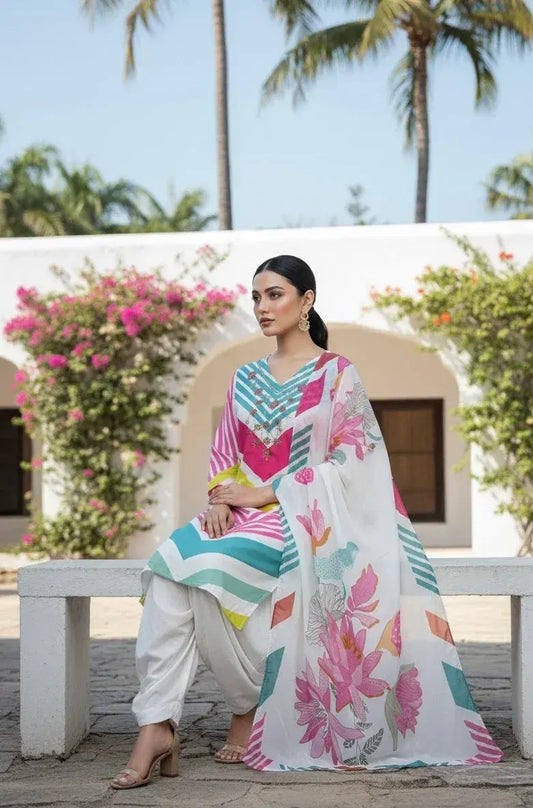 Woman in soft silk ethnic wear with colorful floral dupatta, sitting outdoors in a garden setting