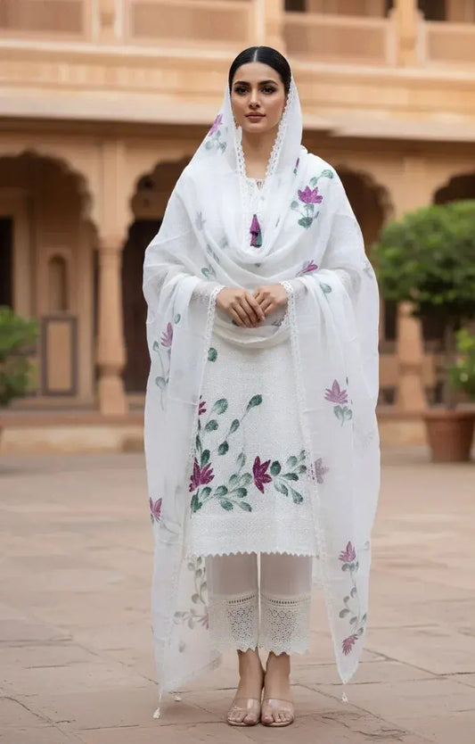 Woman in white embroidered ethnic suit with floral dupatta, standing outdoors