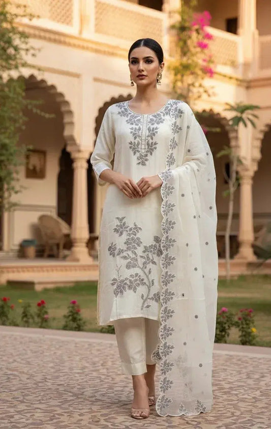 Woman in ivory ethnic suit with floral embroidery and dupatta, outdoor courtyard