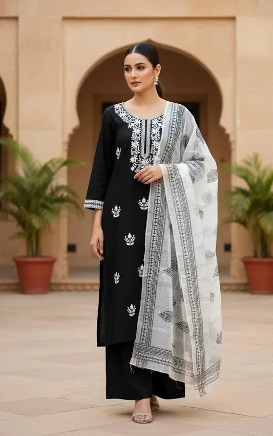 Woman wearing a black and white embroidered ethnic suit with dupatta, standing outdoors