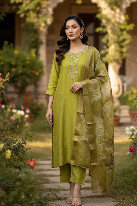 Woman in olive green silk salwar suit with embroidered neckline and dupatta, garden setting