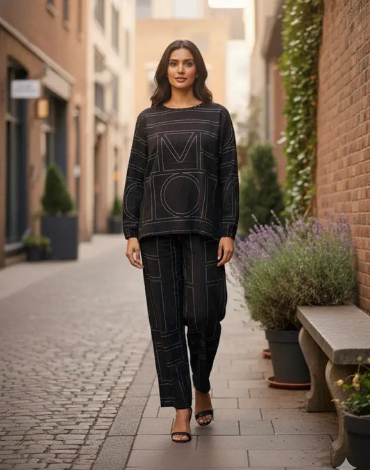 Woman modeling a black ethnic co-ord set with geometric patterns, walking on a city street.