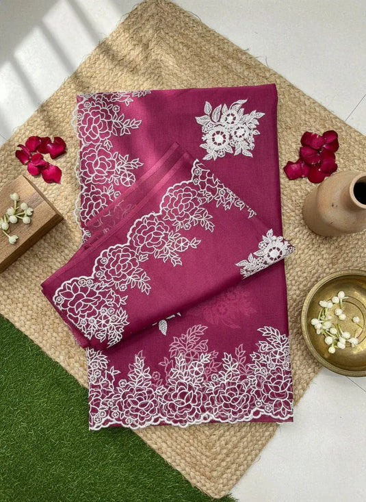 Magenta silk saree with intricate white floral embroidery, displayed with flower petals