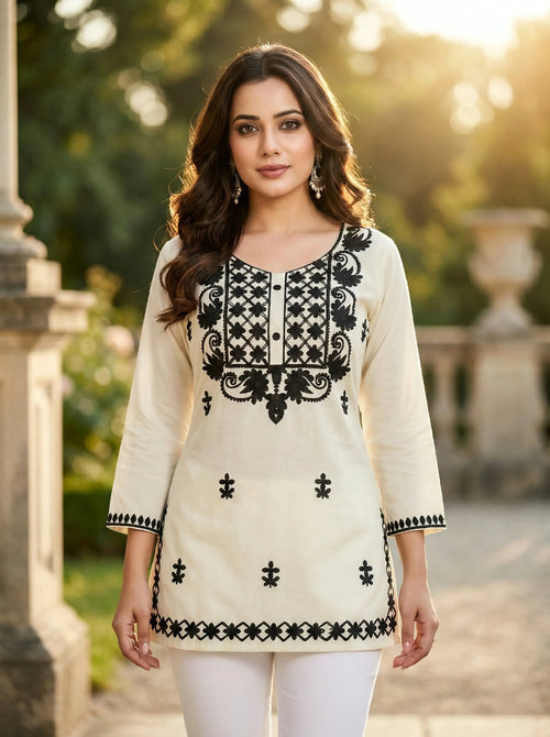 Woman wearing a cream tunic with black embroidery, luxury ethnic wear, outdoor setting