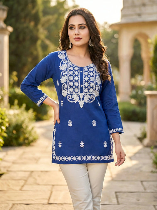 Woman wearing blue embroidered kurti and cream pants, elegant ethnic wear, outdoor setting