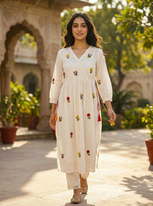 Woman wearing cream embroidered kurta set with floral motifs in an outdoor ethnic setting