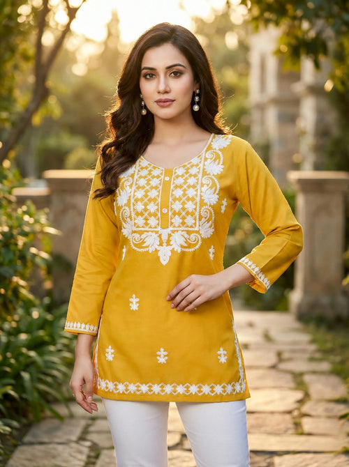 Woman in yellow embroidered kurti with white pants, standing outdoors in elegant ethnic wear