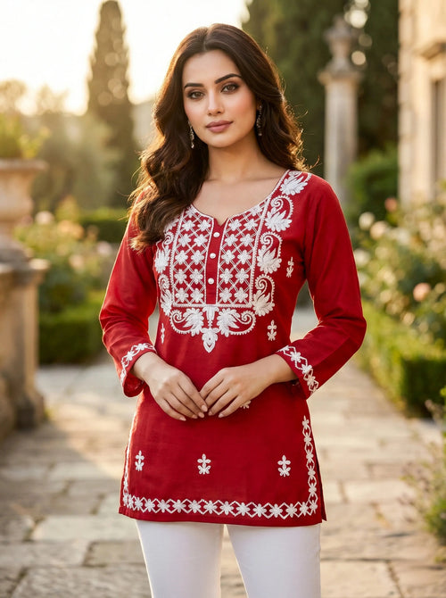 Woman wearing red embroidered kurta with white floral patterns in garden setting
