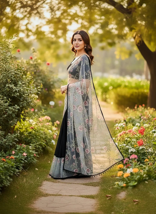 Woman in a soft silk floral saree standing in a sunlit garden with blooming flowers