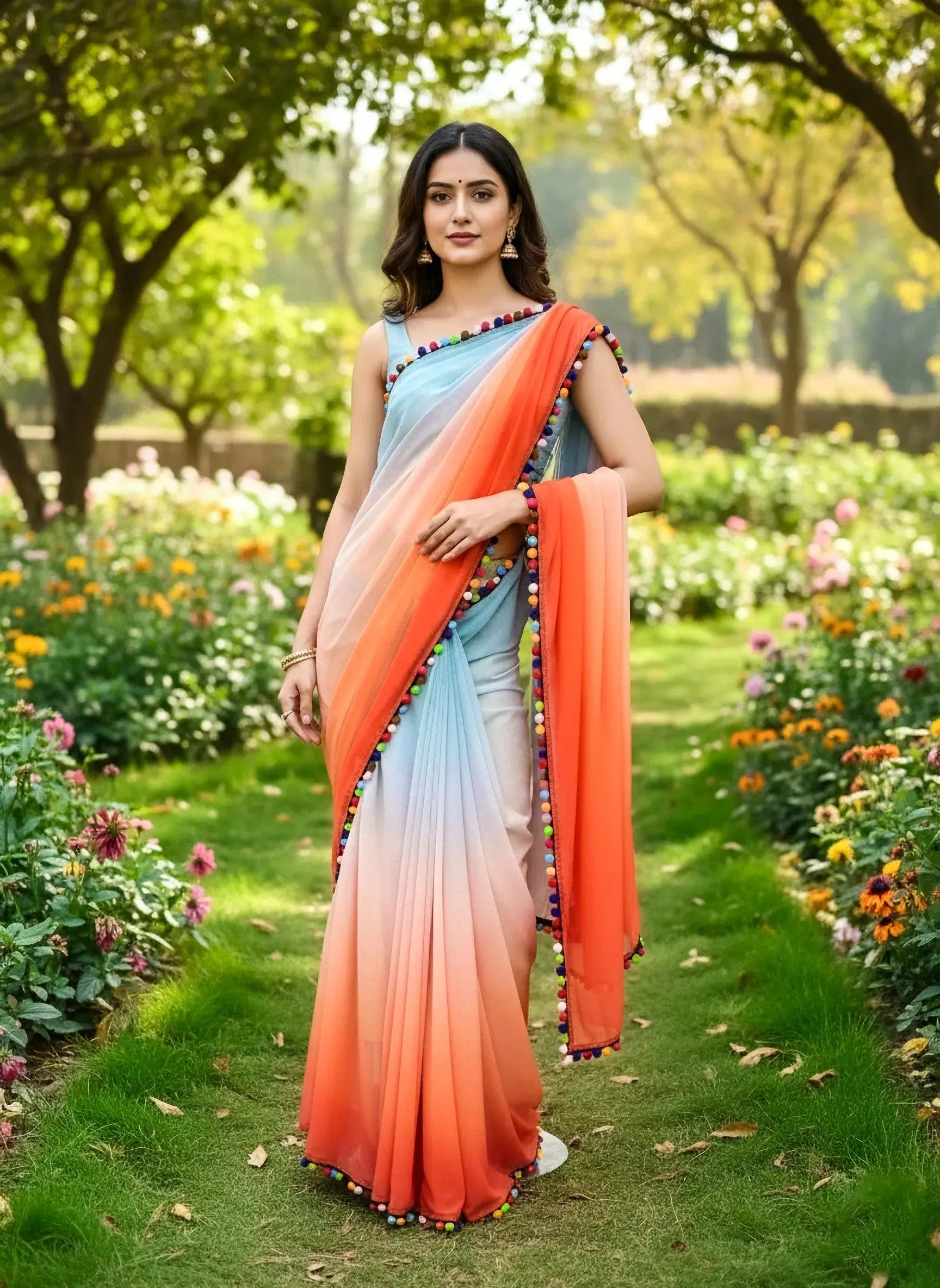 Woman wearing a gradient orange and blue soft silk saree with pompom trim in a garden