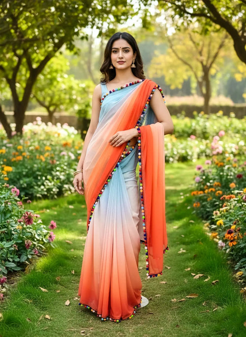 Woman wearing a gradient orange and blue soft silk saree with pompom trim in a garden