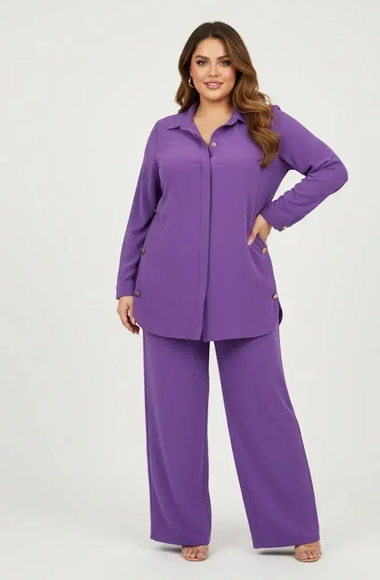 Woman wearing a purple button-down tunic and wide-leg pants set, posing on a plain background