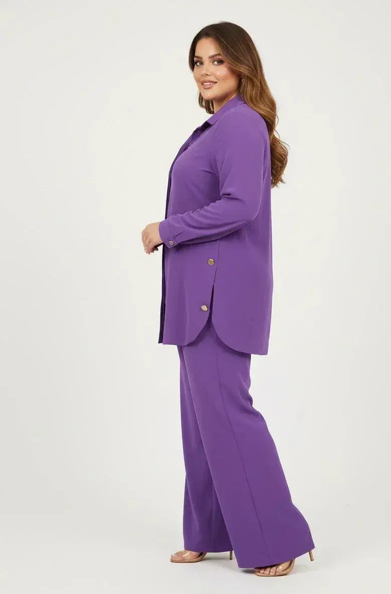 Woman modeling a purple pantsuit with gold buttons and wide-leg trousers, side view
