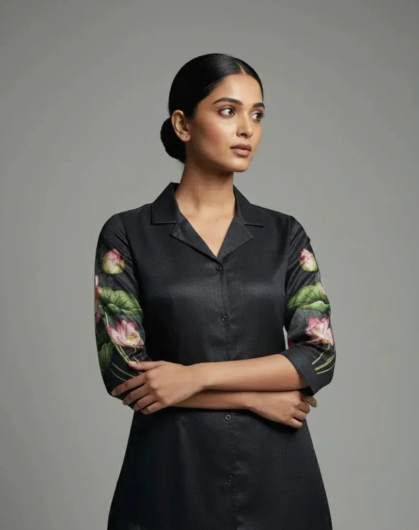 Woman wearing a black silk kurta with floral embroidered sleeves, minimal background