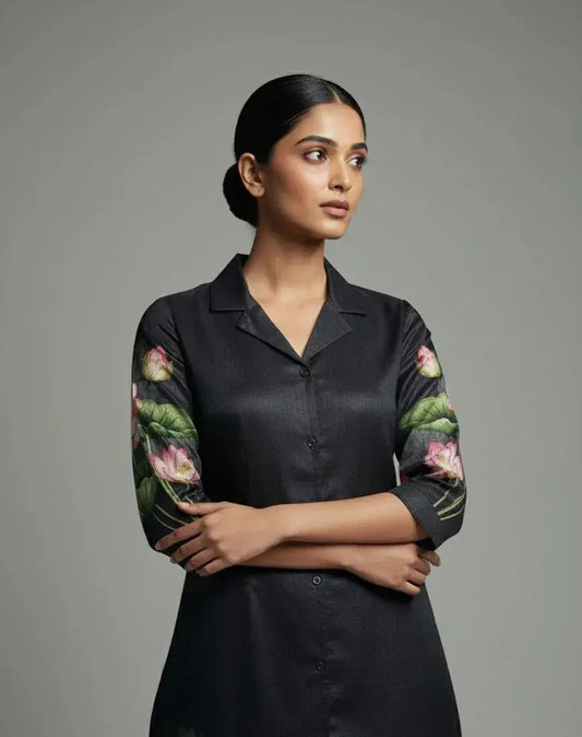 Woman wearing a black silk kurta with floral embroidered sleeves, minimal background