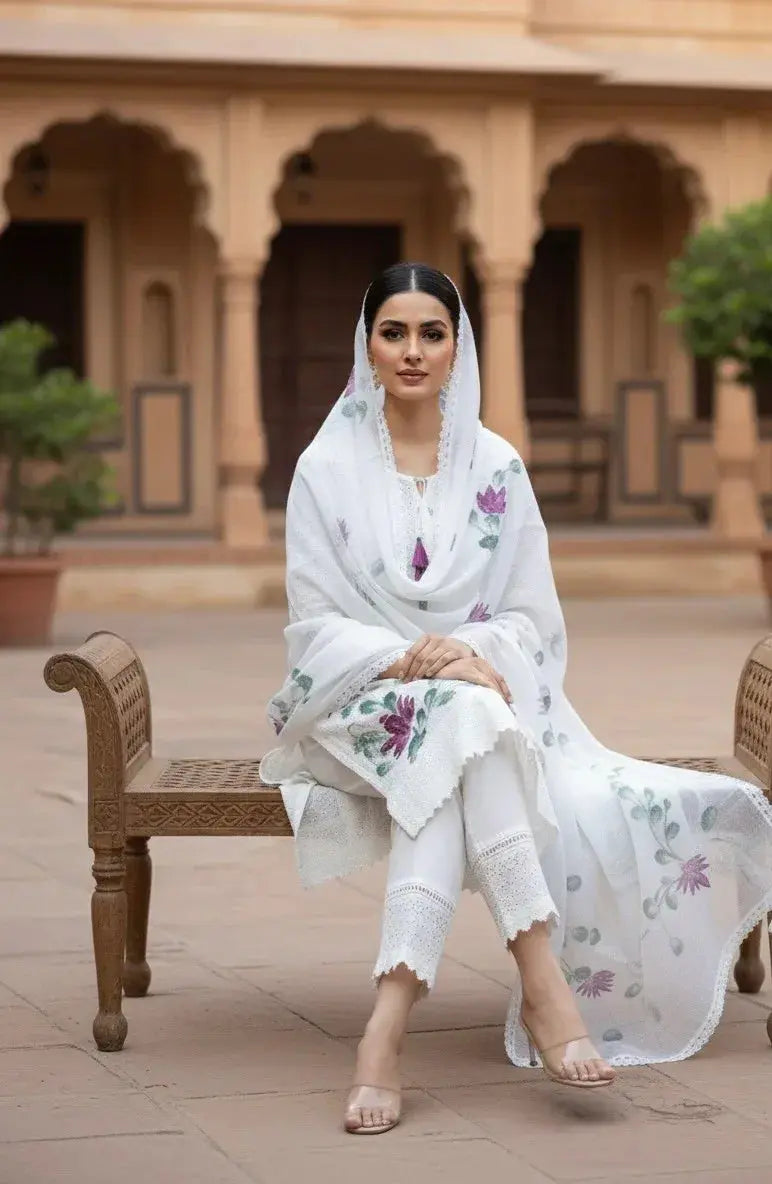 Woman in white embroidered ethnic suit and dupatta sitting in a traditional courtyard