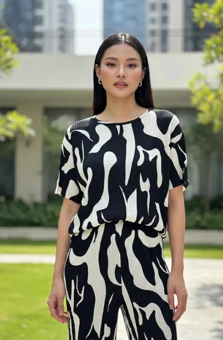 Woman wearing a black and white abstract print co-ord set, standing outdoors