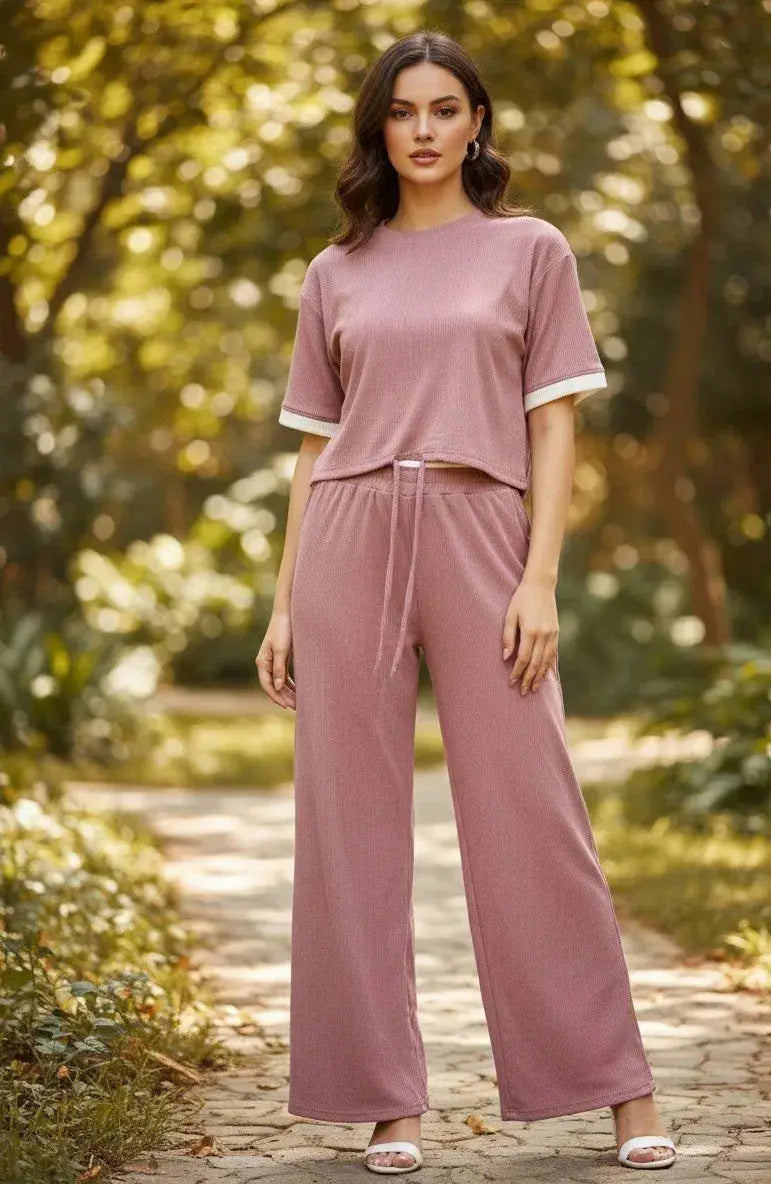 Woman in a mauve loungewear set with short sleeves and wide-leg pants standing outdoors