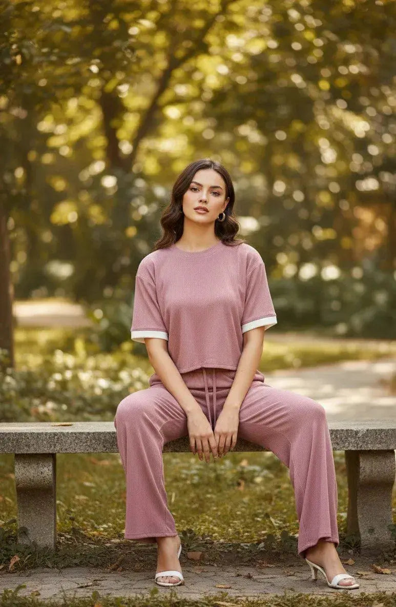Woman in mauve lounge set with wide leg pants sitting on stone bench outdoors
