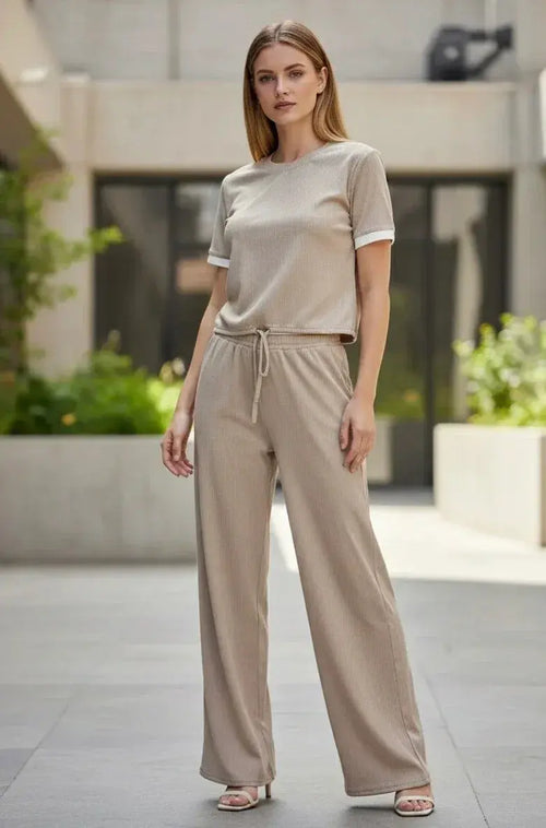 Woman wearing beige lounge set with wide-leg pants and short sleeve top outdoors
