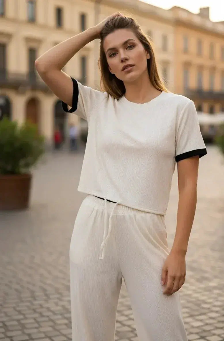 Woman in cream lounge set with drawstring pants and black trim, posing outdoors on a city street