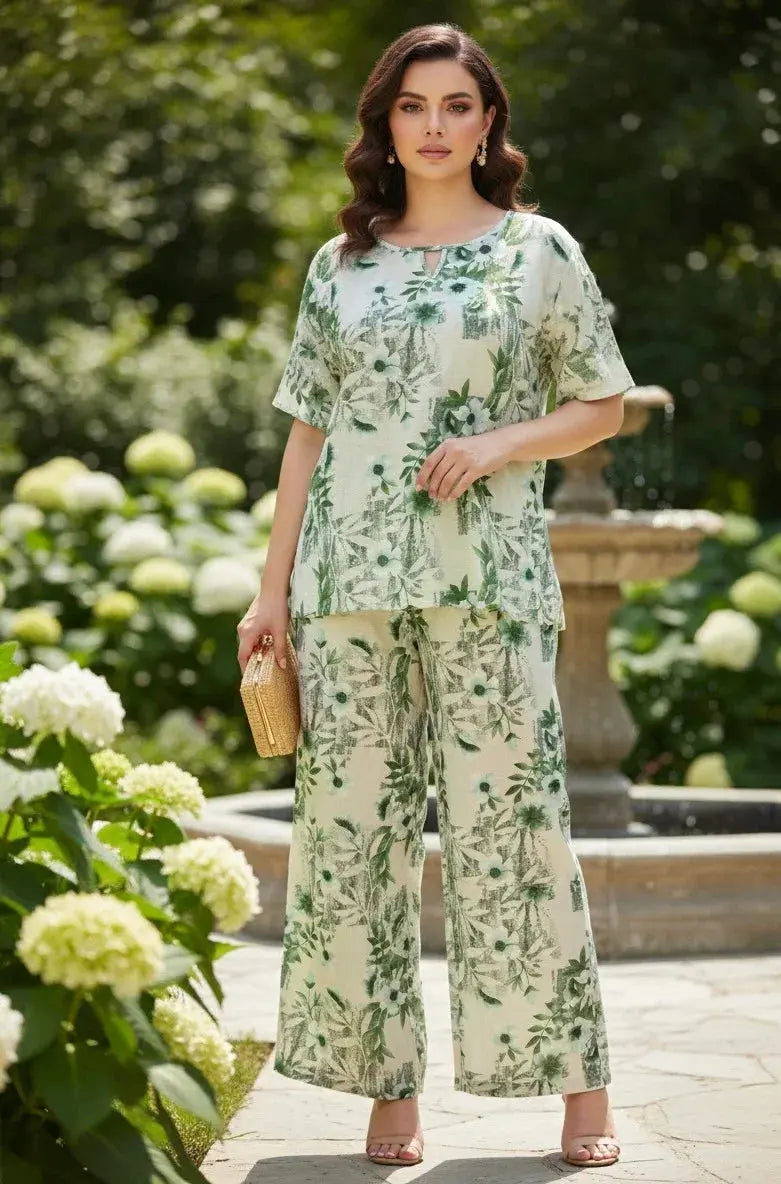 Woman in green floral printed co-ord set with wide-leg pants, holding woven clutch, standing outdoors.