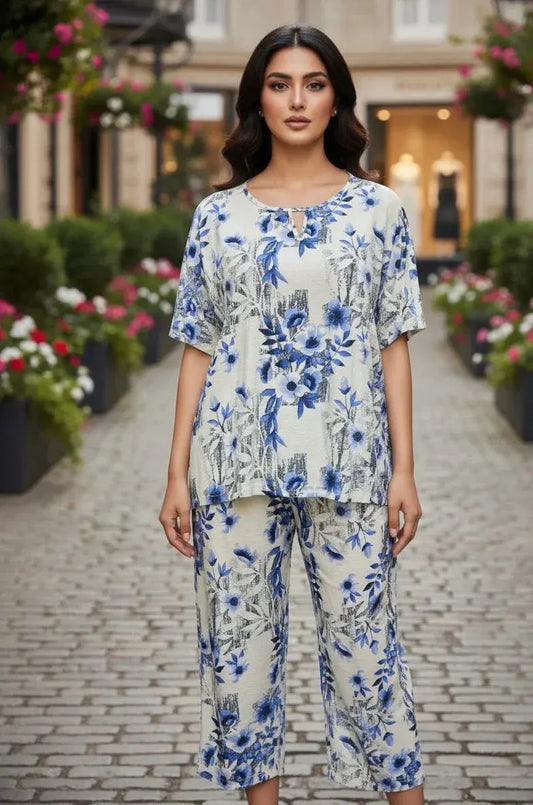 Woman wearing a blue floral printed loungewear set, standing outdoors on a cobblestone path
