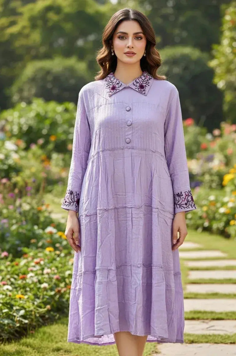 Woman wearing a light purple midi dress with embroidered collar and cuffs in a garden
