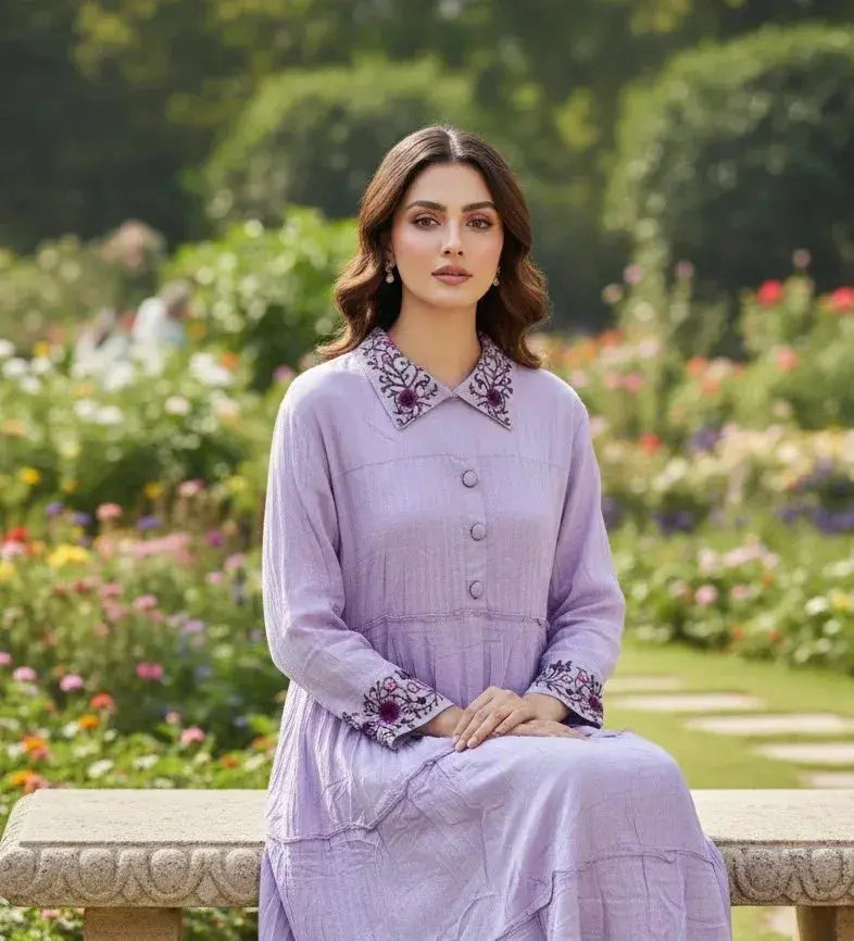 Woman in lilac embroidered ethnic dress seated on a stone bench in a blooming garden