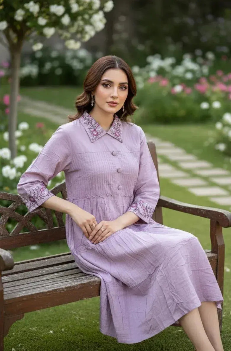 Woman in a lilac embroidered kurta dress sitting on a wooden bench in a flower garden