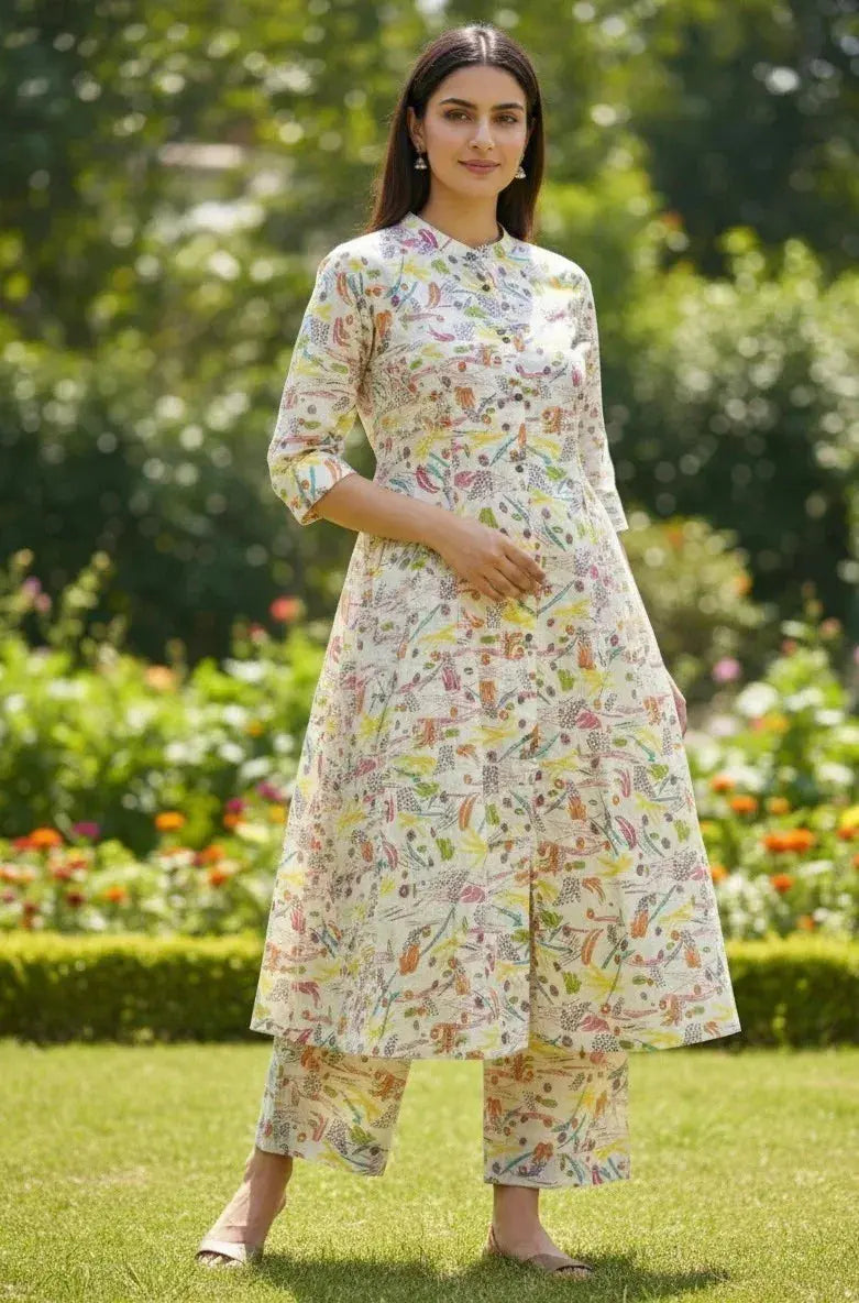 Woman wearing a floral printed kurta set with pants, standing in a garden with greenery.