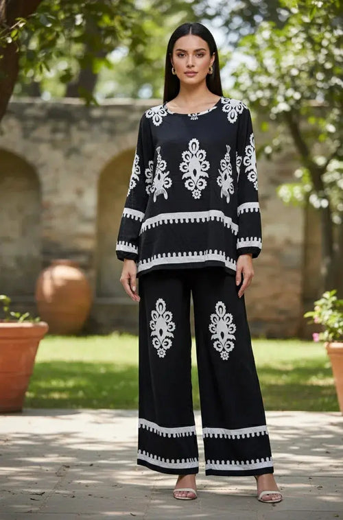 Woman wearing a black ethnic co-ord set with white floral embroidery outdoors