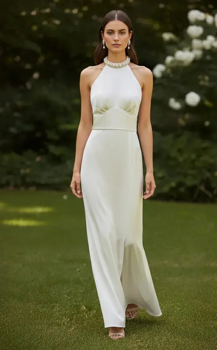 Woman in elegant white silk gown with halter neck, pearl jewelry, outdoor garden setting