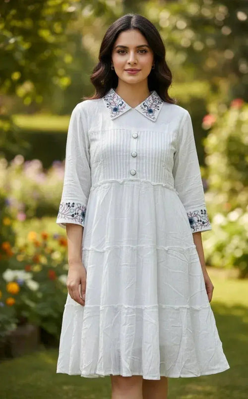 Woman in a white cotton dress with floral embroidered collar and sleeves in a garden